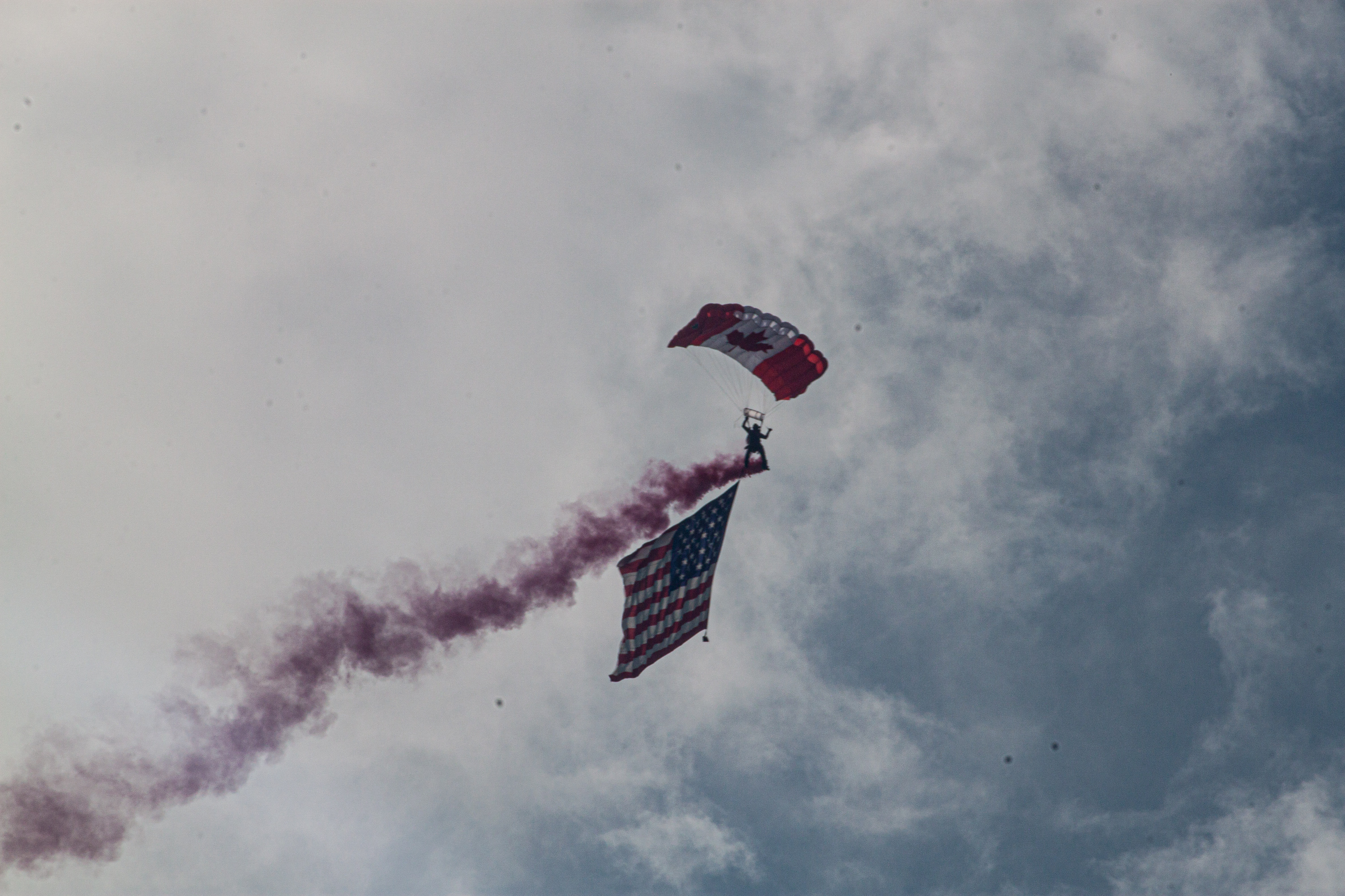 Parachutist diving with Canadian flag smoke
